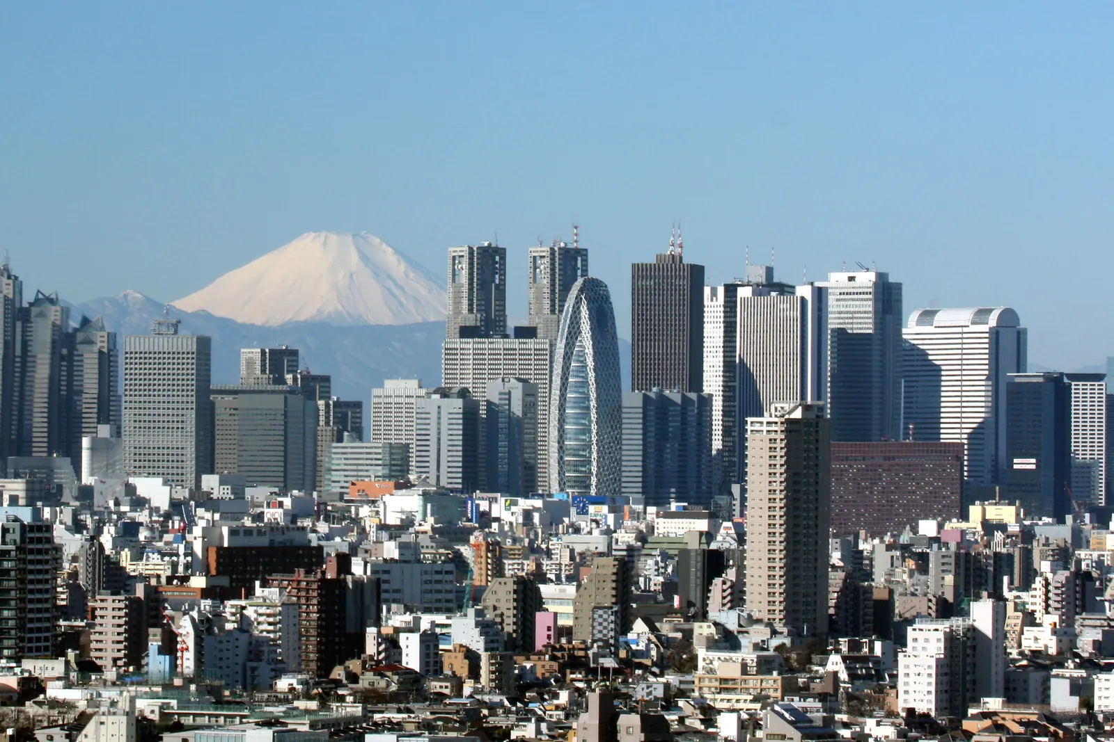 Skyskrabere i Shinjuku, Tokyo, rager op over lave bygninger med den snedækkede Mount Fuji i horisonten